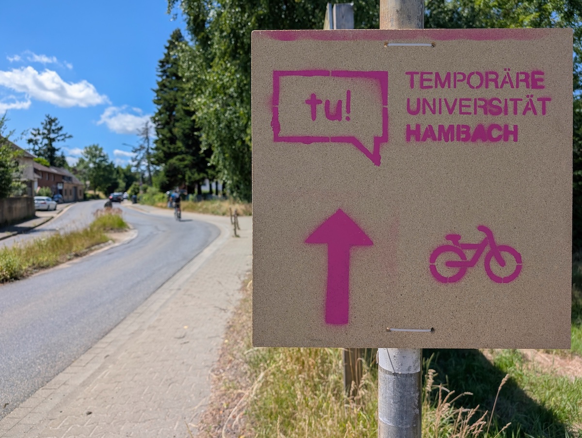 A sign displaying the pink inscription “Temporary University Hambach.”
