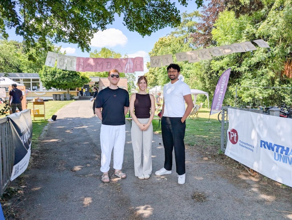 Ferdinand Berghof (student assistant), Julia Knapp, and Sharon Nathan (research associates) are standing at the entrance of tu! Hambach.
